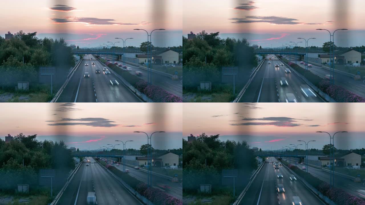 从道路安全铁丝网后面的立交桥拍摄的日落时高速公路的4k视频延时。