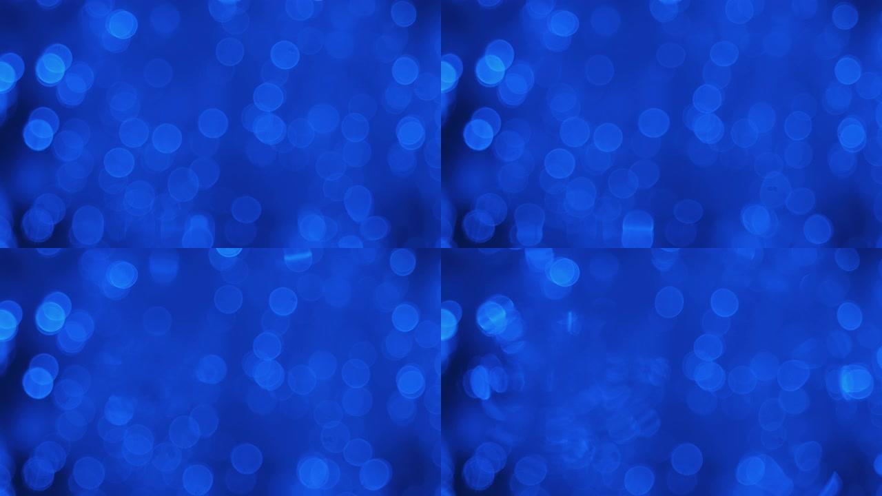 发光的背景是移动的蓝色灯光和一滴水，落入水中。散焦背景。