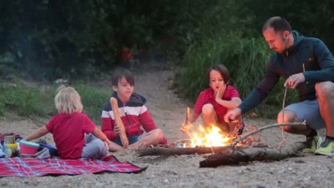 家庭，孩子在夏季河边的傍晚野餐和篝火
