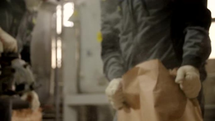 戴着面具的工人用混凝土填充和包装纸袋