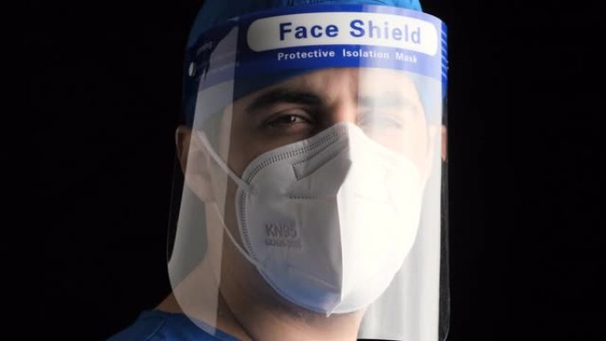 沉思疲倦的年轻男性医护人员看着戴着n95防护面罩和面罩的相机