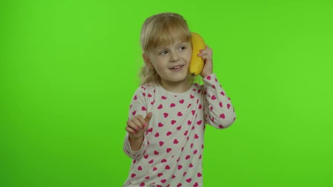 快乐的女孩孩子模仿电话交谈香蕉孤立在色度关键背景