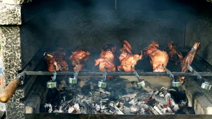 烧烤火盆的特写视图在金属串上烹饪大火鸡或鸡肉腿，在燃烧的煤上燃烧着火焰和烟雾。传统的东欧烧烤派对在家