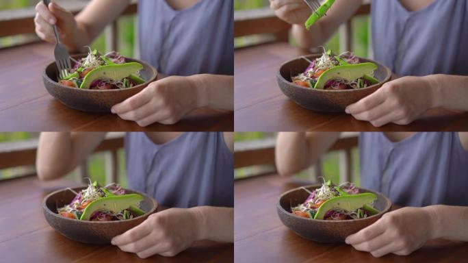 一个热带咖啡馆的年轻女子吃健康的素食沙拉。素食概念。慢动作镜头