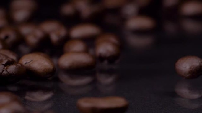 惊人的质量。超级慢动作拍摄的优质新鲜烤棕色咖啡豆滚动，落在木桌上，深色背景。咖啡谷物关闭4k视频