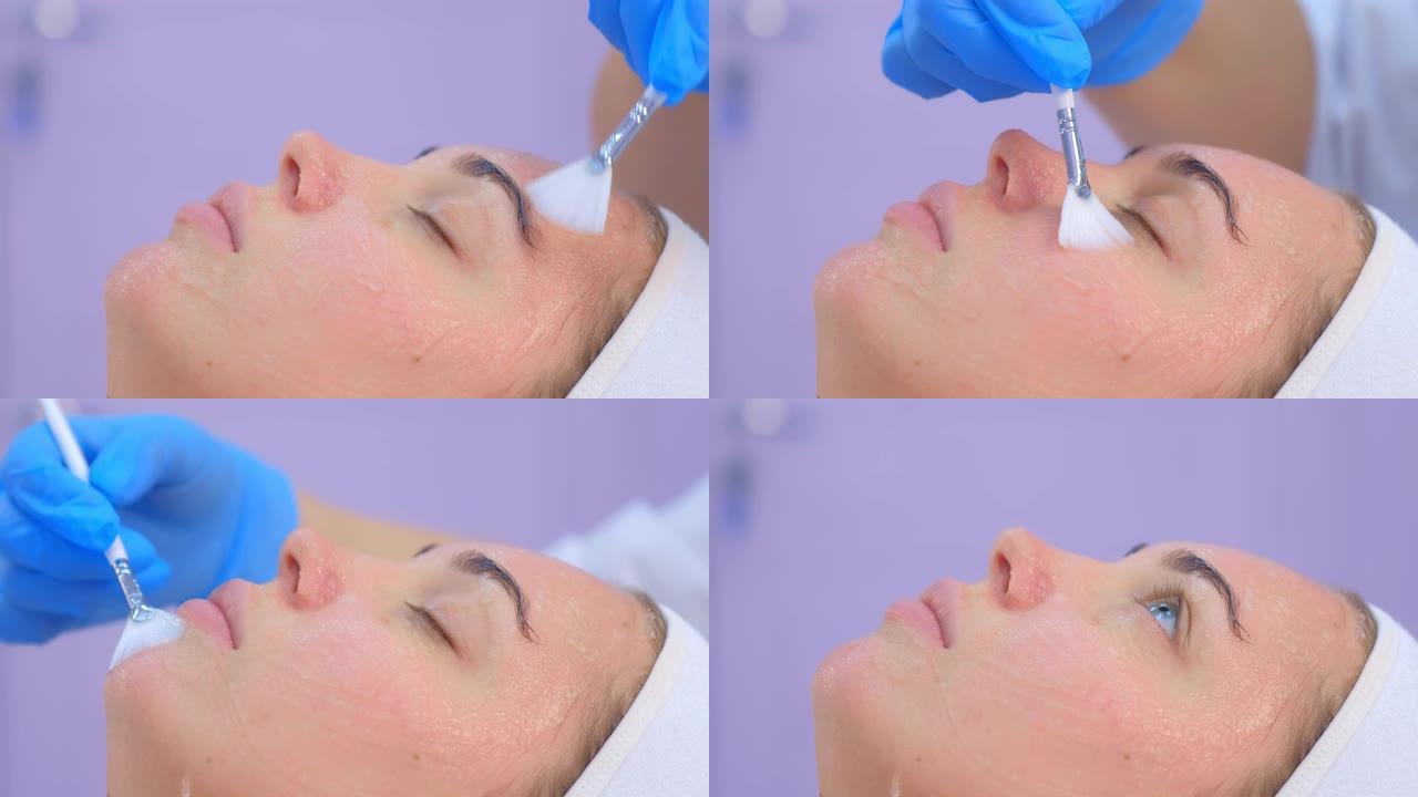 美容师在语音电泳手术前在女性脸上涂抹凝胶。