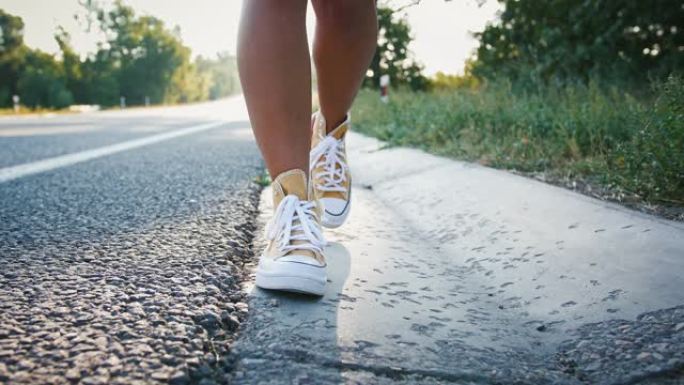 穿着黄色运动鞋在路上行走的女性腿的特写