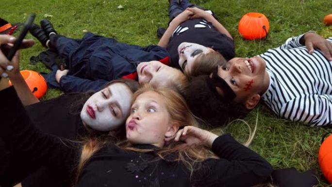 五个孩子穿着万圣节服装躺在草地上