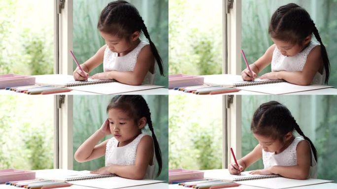 快乐的亚洲儿童学生或小女孩drawig coorig铅笔，喜欢在冠状病毒期间在白纸上写字，检疫呆在家
