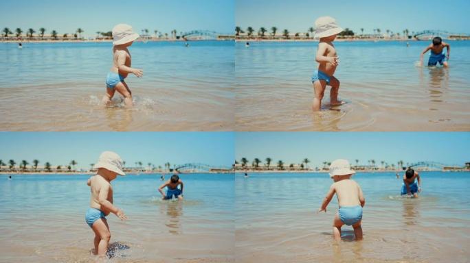可爱的男婴在海水中迈出第一步。可爱的小孩泼水