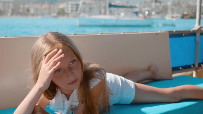 快乐的女孩躺在海上航行的游艇上。年轻的少女在海上游船上放松。暑假乘坐海船旅行的旅游女孩。