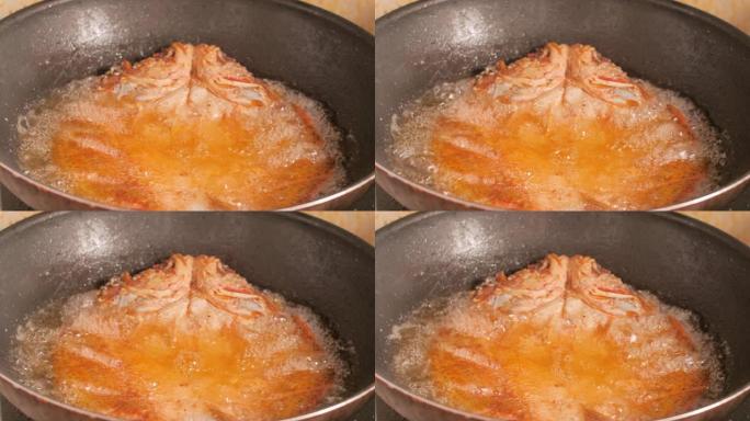 在黑锅中油炸的鱼的特写镜头