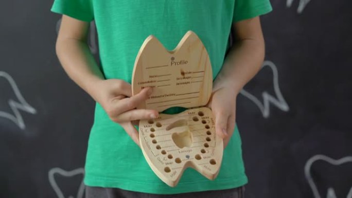 小男孩展示了一个用来装乳牙的木盒子。儿童牙齿改变的概念