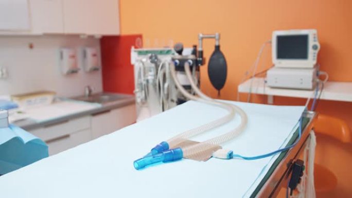 在动物手术期间关闭用于人工肺通气的设备，在手术室中配备手术台和转向计算机。模糊的橙色墙壁和背景的水槽
