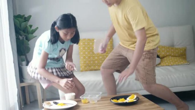 快乐的亚洲男孩和他的妹妹在家一起做零食后帮忙打扫，生活方式理念。