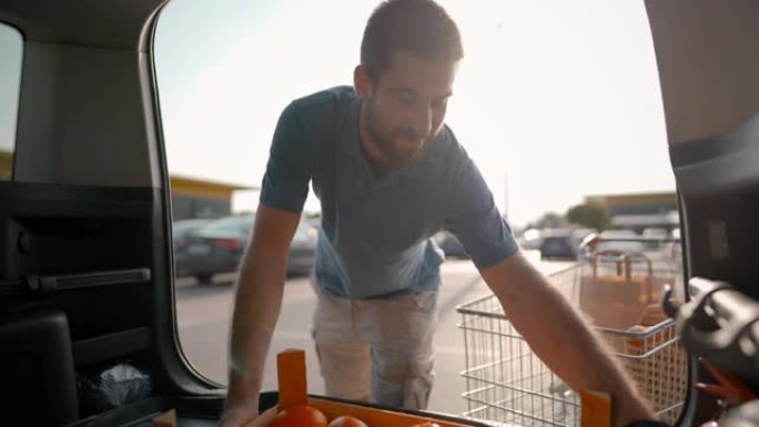 年轻人从超市将杂货包装到停车场的汽车后备箱中