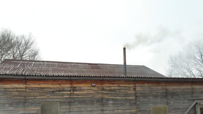 烟从房子的烟囱里冒出来。屋顶上的管道。有烟囱的房子。蓝天下的烟。