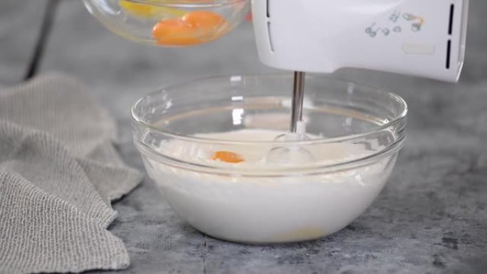 在装有蛋糕面糊的碗中加入蛋黄。用搅拌器混合蛋糕面糊