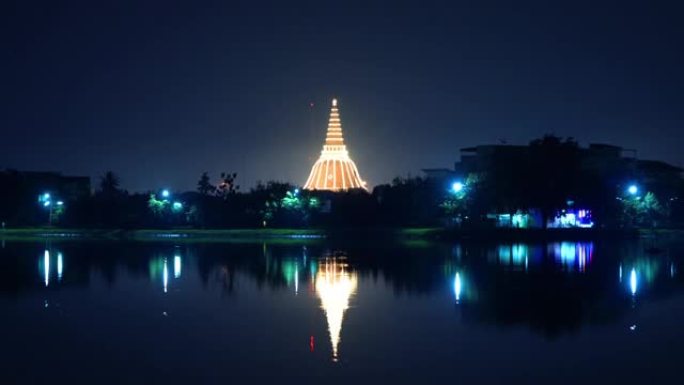 Phra Pathommachedi寺庙的天际线，夜晚有倒影。带有民居的金色佛教宝塔，泰国纳康帕通区
