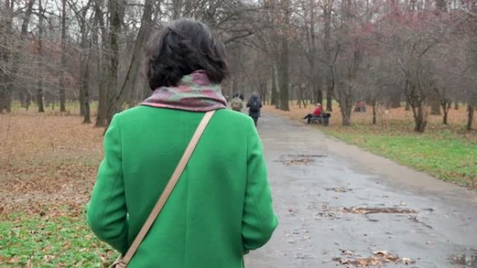 秋天的一天，一个女人走公园人行道，人们从后面走慢动作