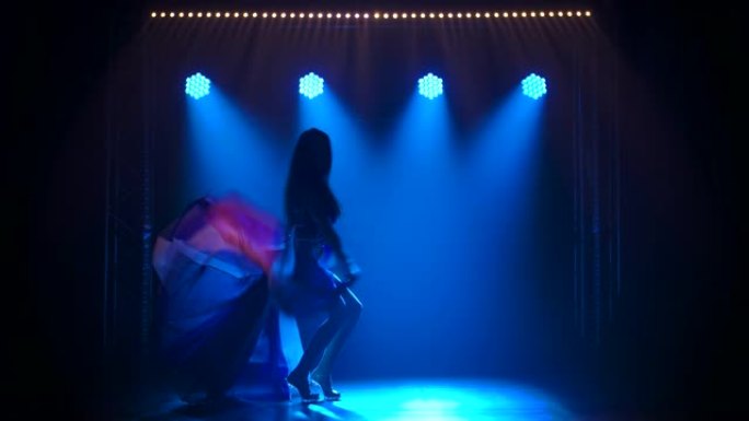 剪影苗条的高女人穿着性感的西装跳舞，穿着英国国旗和水钻的颜色。在黑暗的工作室拍摄，带有烟雾和蓝色霓虹