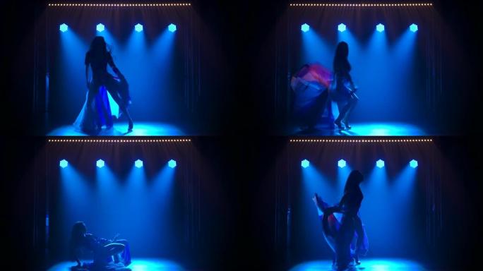 剪影苗条的高女人穿着性感的西装跳舞，穿着英国国旗和水钻的颜色。在黑暗的工作室拍摄，带有烟雾和蓝色霓虹