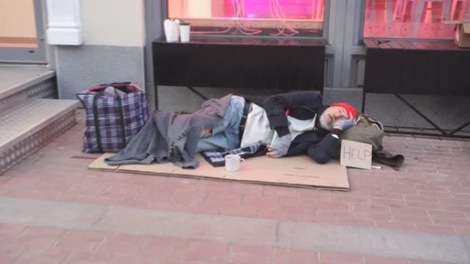 绝望的乞丐男人穿着旧衣服躺在纸板箱上