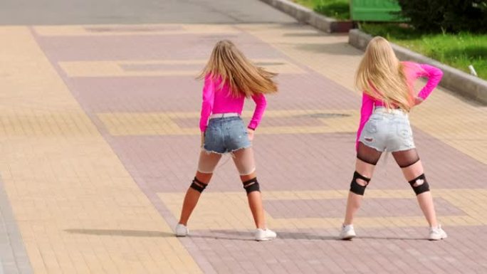 在宽阔的街道上，穿着短裤跳舞的年轻开朗女孩的二重奏。慢动作