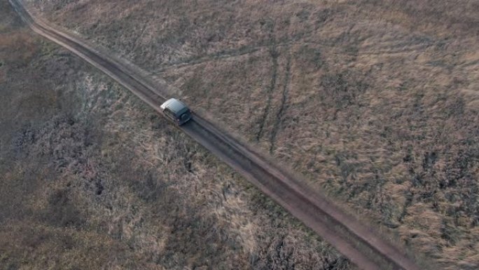 越野车黑色跨界车行驶在乡村道路上鸟瞰图。越野车在土路上行驶，穿过村庄的乡村。