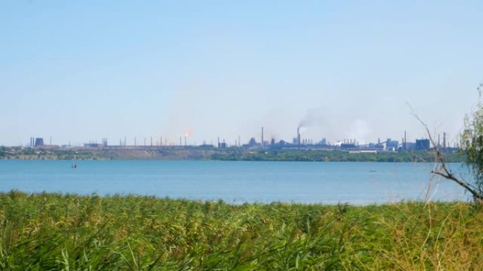 工业区，从工厂管道中冒出浓浓的白色和黑色浓烟，与蓝天形成鲜明对比。环境污染。工厂烟囱在阳光明媚的日子