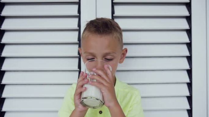 一个健康的小男孩和一杯牛奶的肖像。一个男孩正在白门里喝牛奶。健康饮食。正确的生活方式。小男孩喝牛奶