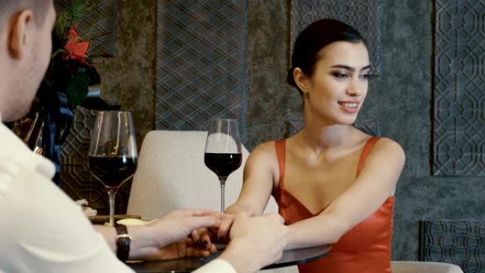 年轻漂亮的女人和男人在餐厅牵手约会。4K