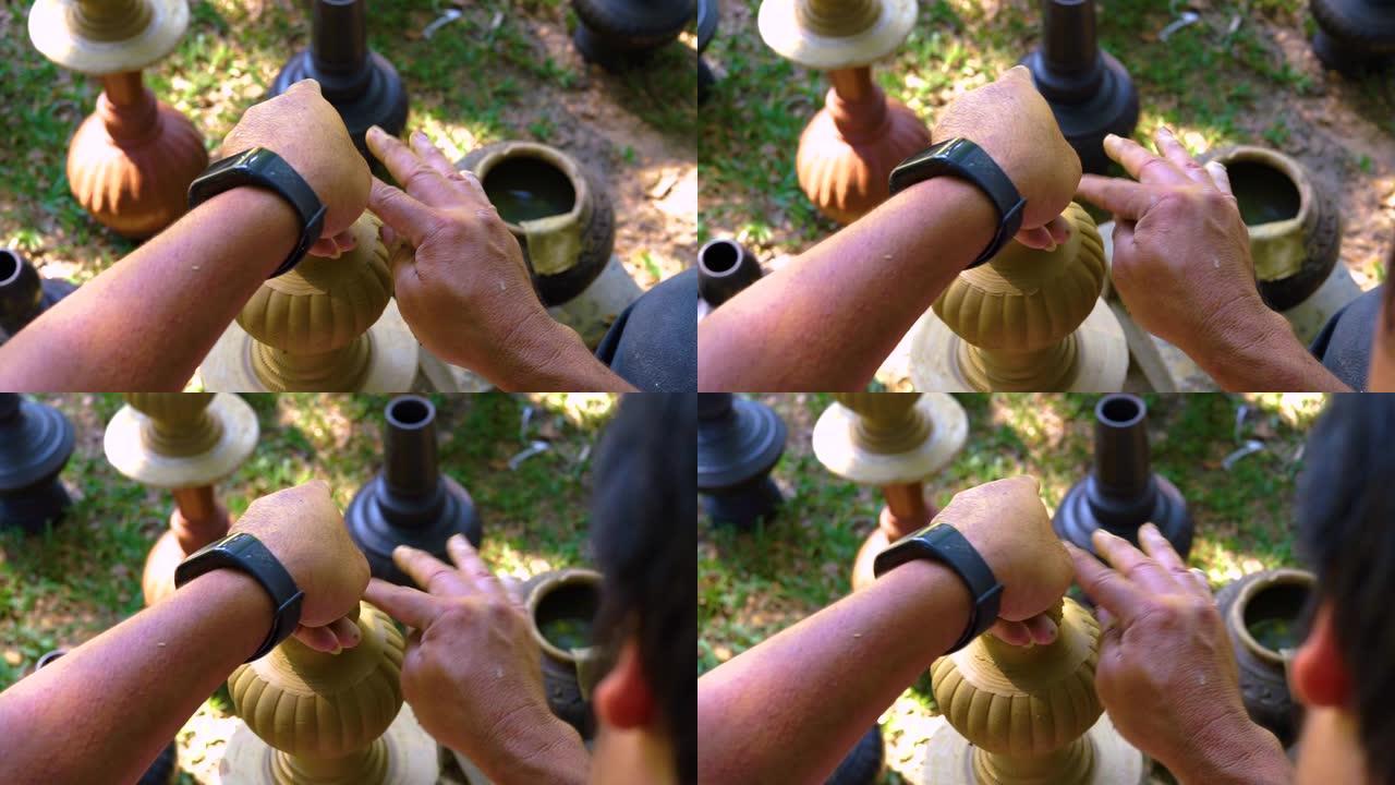 陶轮上创造的粘土陶工。陶轮上新鲜湿粘土的雕刻家。选定焦点。波特是在露天锅中生产的。