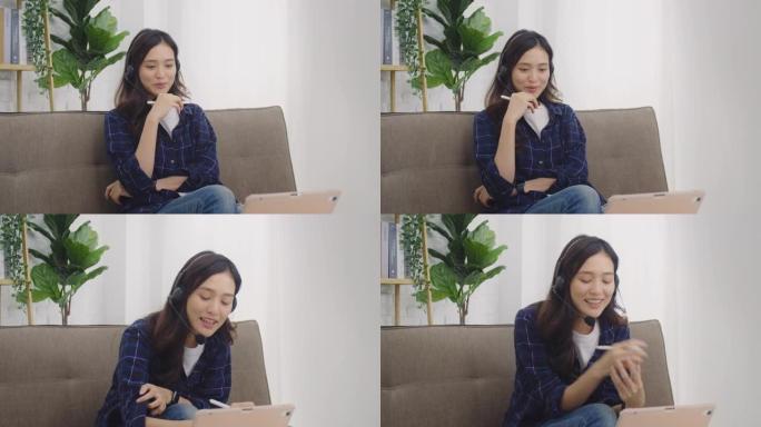 年轻的亚洲妇女戴着耳机并使用平板电脑。在家中的房间里通过视频在线通话与相机交谈。4k
