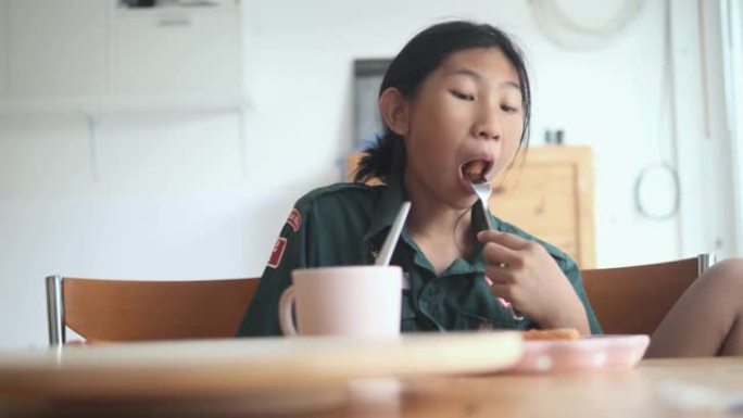 穿着制服的亚洲女学生上学前和哥哥在家吃早餐，生活方式理念。