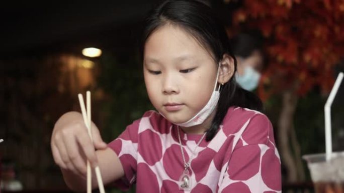 亚洲女孩在餐厅和家人一起吃日本食物，生活方式理念。