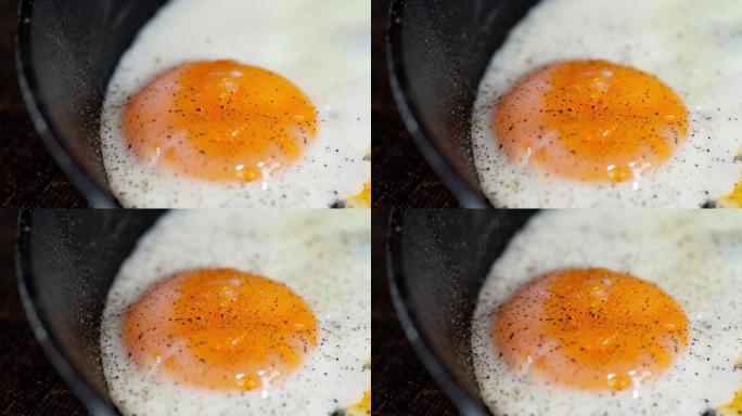 在撒上胡椒粉的煎锅里煎鸡蛋。