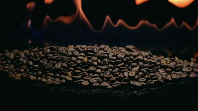 黑色背景上火焰中的烘焙咖啡豆。烘焙咖啡的过程