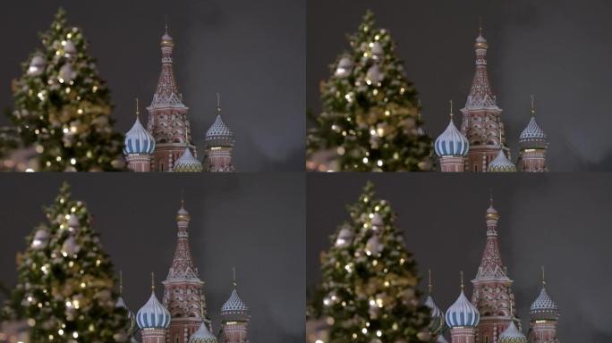 俄罗斯新年在红场的莫斯科。红场上的圣巴西尔主教座堂。飘落的雪。用球和花环装饰的新年树。
