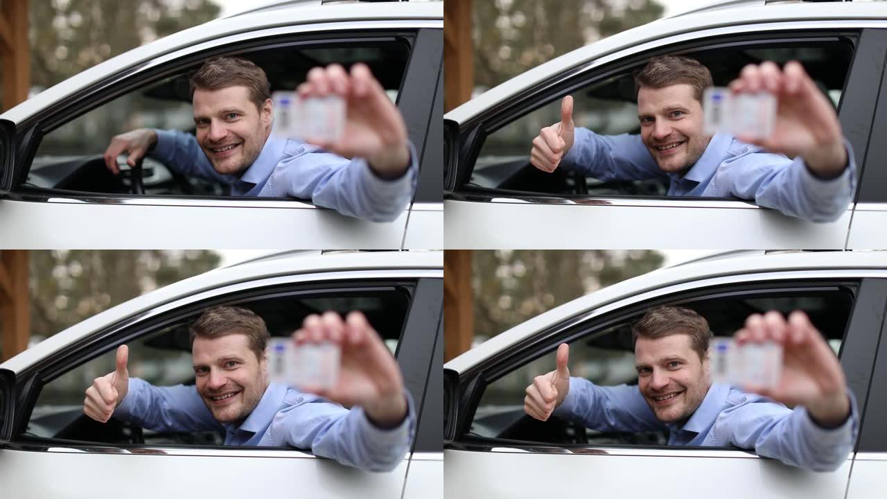 年轻的快乐男人坐在车里，竖起大拇指展示他的新驾照