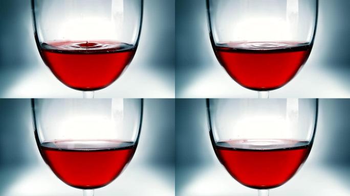创意微距慢动作视频红酒在一杯和一滴落的酒。酒杯上慢慢落下的酒滴特写。