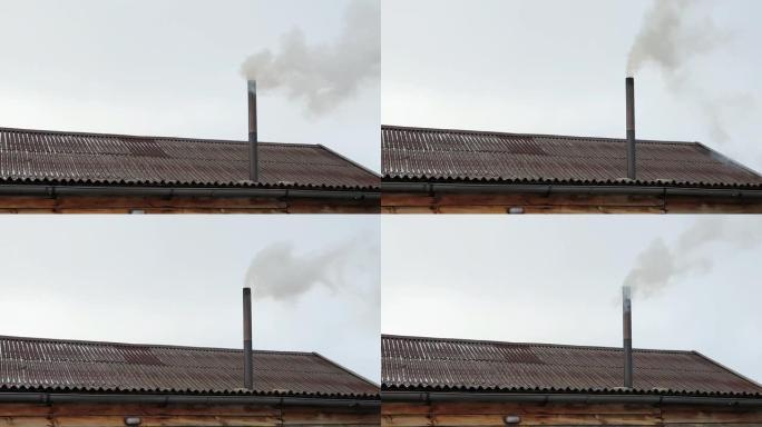 烟从房子的烟囱里冒出来。屋顶上的管道。有烟囱的房子。蓝天下的烟。