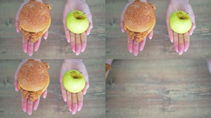 在卡路里汉堡和青苹果之间进行选择。妇女手握有害健康食品