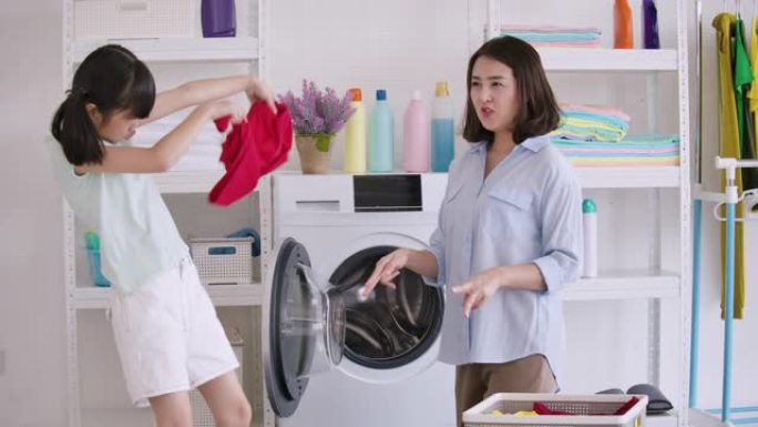 亚洲母亲和孩子洗衣服。妈妈和女儿有时间在家一起打扫。