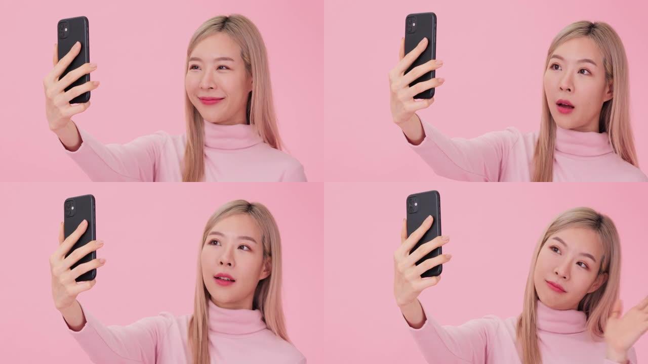 年轻的韩国妇女在粉红色背景下给她的朋友打视频电话。
