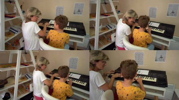 女人在康复中心的音乐治疗期间帮助小男孩玩合成器