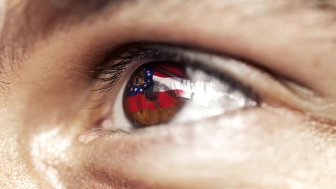 近距离看，棕色眼睛的人，鸢尾色的乔治亚州国旗，随风飘扬的美利坚合众国。视频的概念