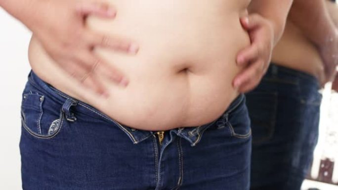 超重的女人检查她肚子上的脂肪。肥胖问题