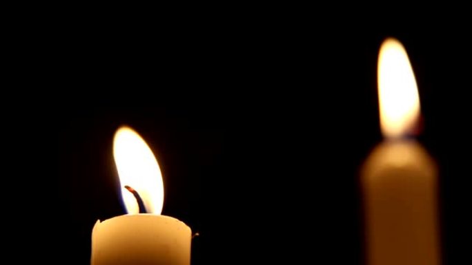 木制烛台上的蜡烛晚上在黑色背景上燃烧。