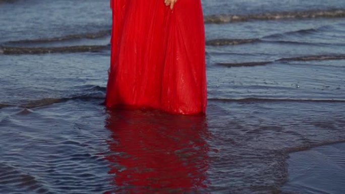 长发黑发女人站在海水中拿着连衣裙下摆
